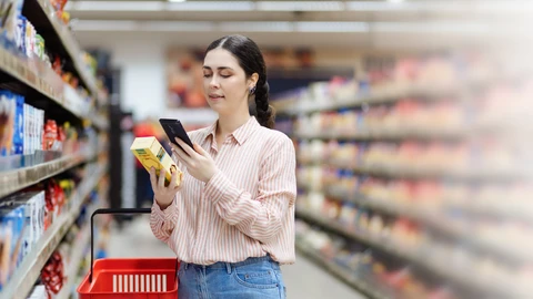 Nainen skannaa älypuhelimellaan tuotepaketin koodin