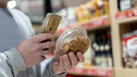 Mies skannaa älypuhelimellaan pähkinäpaketin koodin