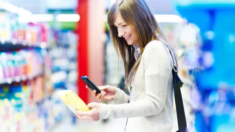 Nainen tutustuu tuotepakkauksen tietoihin