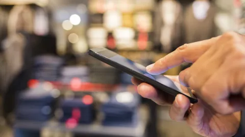 Matkapuhelimen selailu vaateliikkeessä