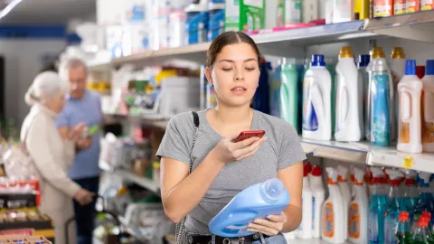 Nainen tutkii pesuaineen tuotetietoja