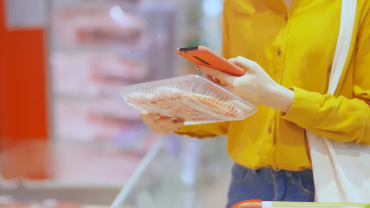 Nainen skannaa älypuhelimellaan tuotepaketin koodin