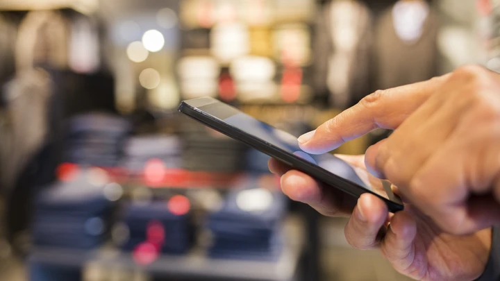 Matkapuhelimen selailu vaateliikkeessä