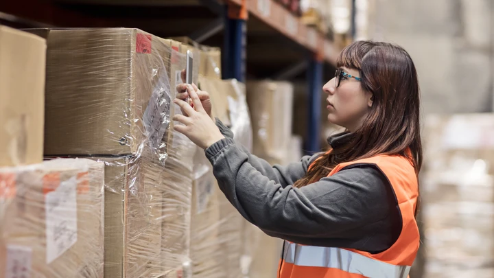 Nainen skannaa varastossa laatikon koodin