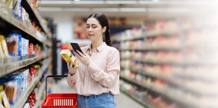 Nainen skannaa älypuhelimellaan tuotepaketin koodin